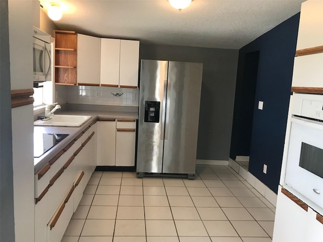 kitchen featuring light tile patterned flooring, sink, white cabinetry, stainless steel appliances, and backsplash