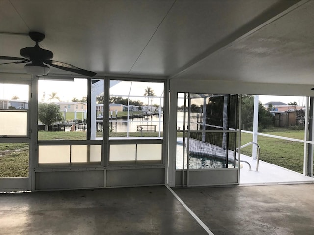 unfurnished sunroom with ceiling fan and a water view