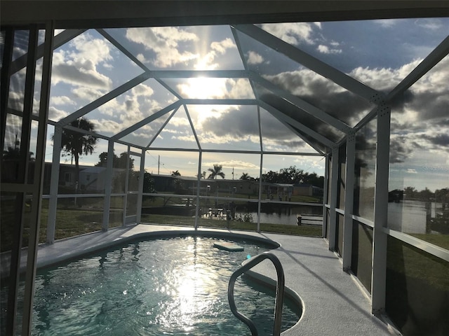 view of swimming pool with a patio, a water view, and a lanai