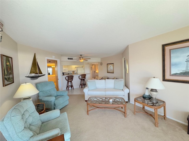 living room with ceiling fan, light colored carpet, and a textured ceiling