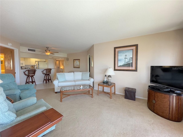 living room featuring ceiling fan, light colored carpet, and a textured ceiling