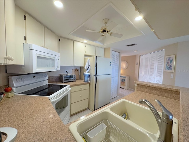 kitchen with light tile patterned flooring, sink, ceiling fan, a raised ceiling, and white appliances