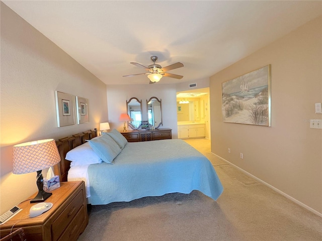 bedroom with ceiling fan, light colored carpet, and connected bathroom