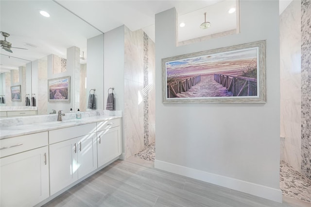 bathroom featuring ceiling fan, tiled shower, and vanity