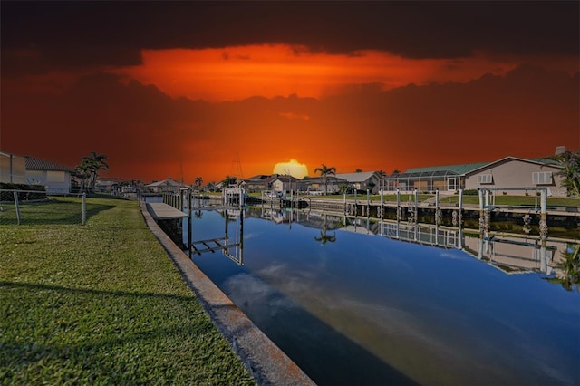 dock area featuring a yard, a water view, boat lift, and a residential view