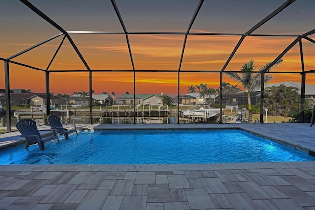 pool featuring glass enclosure, a residential view, and a patio