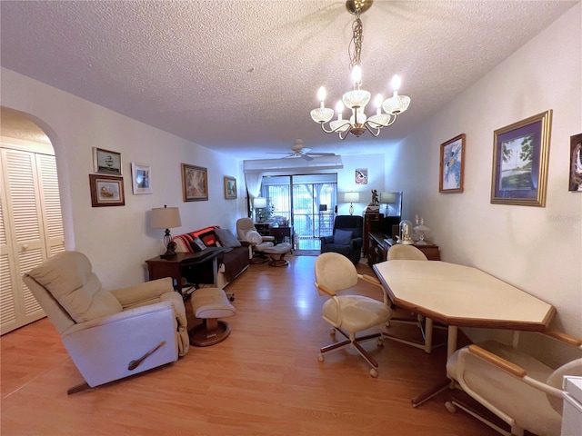 interior space featuring ceiling fan with notable chandelier, a textured ceiling, and light wood-type flooring