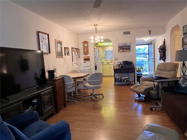 living room with an inviting chandelier, hardwood / wood-style floors, and a textured ceiling