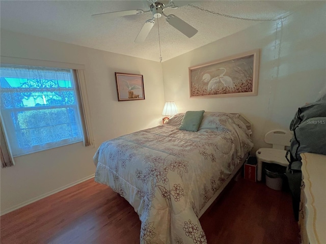 bedroom with ceiling fan, dark hardwood / wood-style flooring, and a textured ceiling