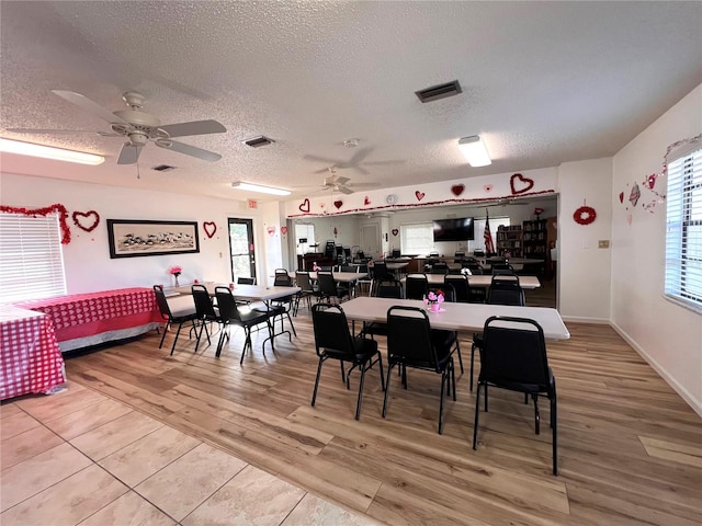 dining space with wood-type flooring, a healthy amount of sunlight, a textured ceiling, and ceiling fan