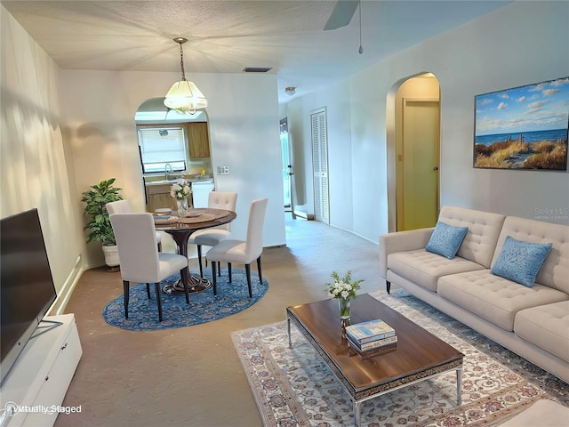 living room featuring sink, concrete floors, and ceiling fan