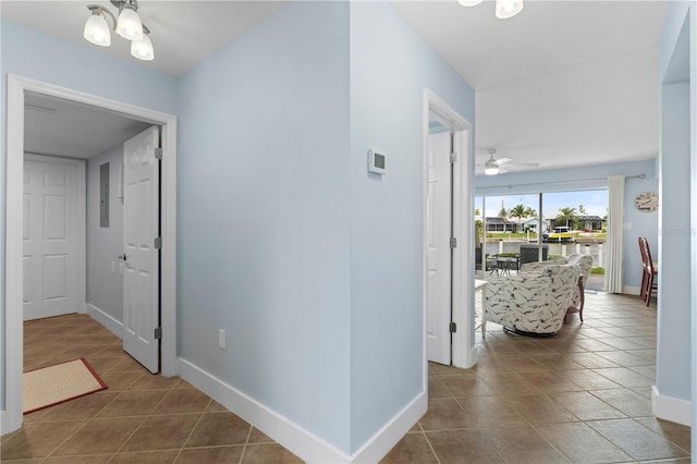 hallway featuring a water view, tile patterned floors, and an inviting chandelier