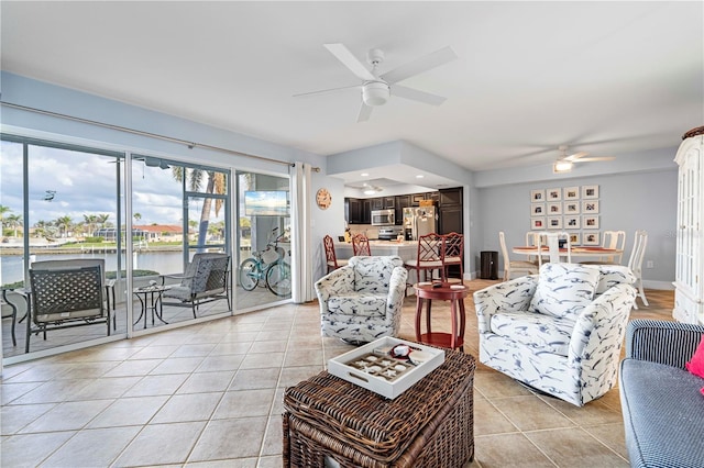 living room with a water view, ceiling fan, and light tile patterned flooring