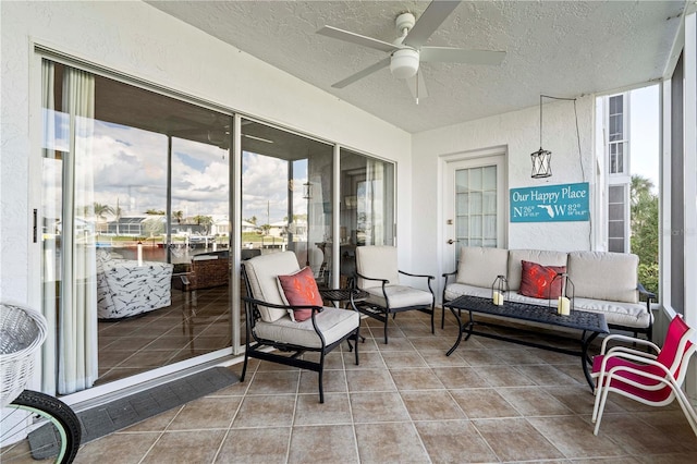 sunroom / solarium featuring ceiling fan and a water view