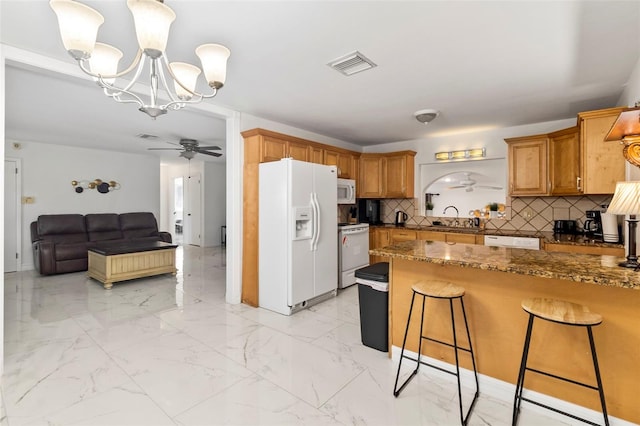 kitchen featuring ceiling fan with notable chandelier, decorative light fixtures, a kitchen bar, kitchen peninsula, and white appliances