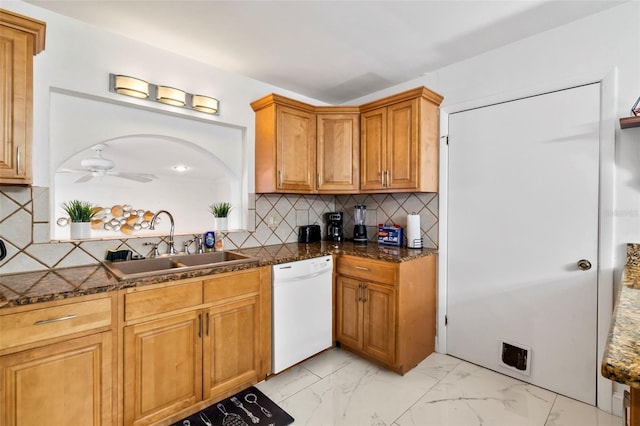 kitchen with tasteful backsplash, sink, dark stone countertops, ceiling fan, and white dishwasher