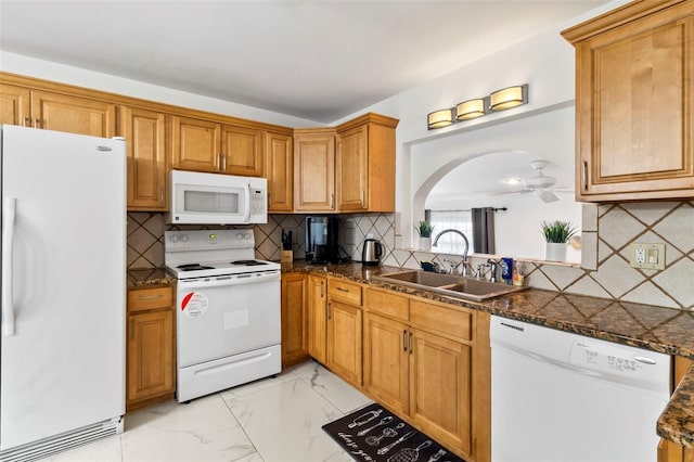 kitchen featuring sink, dark stone countertops, backsplash, and white appliances