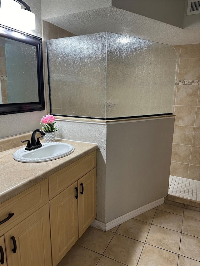 bathroom featuring tile patterned flooring, vanity, and tiled shower