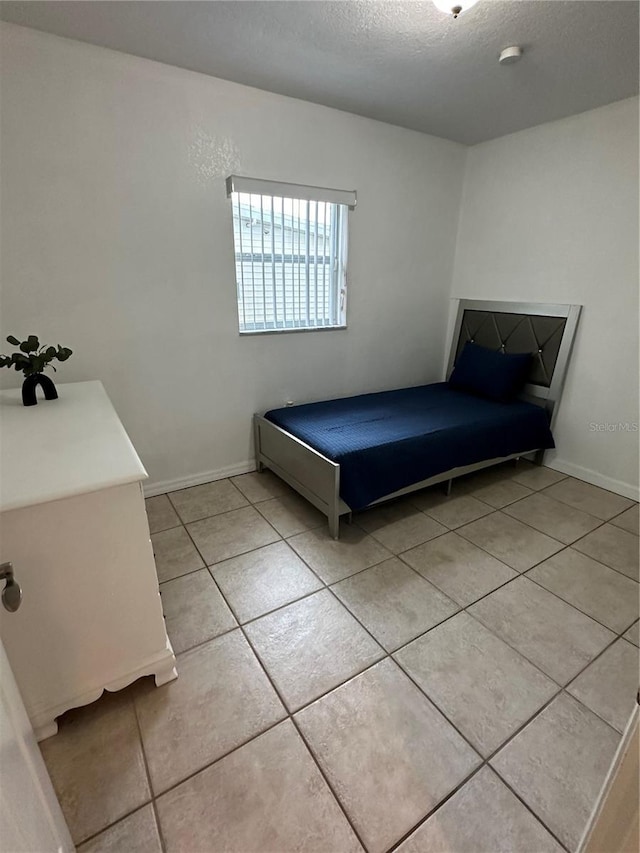 unfurnished bedroom featuring a textured ceiling and light tile patterned floors