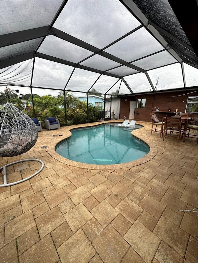 view of swimming pool featuring glass enclosure and a patio area