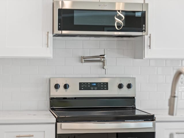 interior details featuring white cabinetry, stainless steel appliances, and backsplash