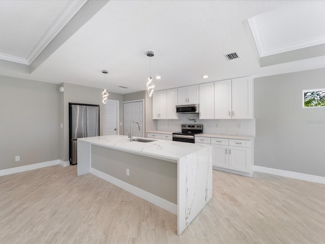 kitchen featuring sink, white cabinetry, stainless steel appliances, light stone countertops, and a kitchen island with sink