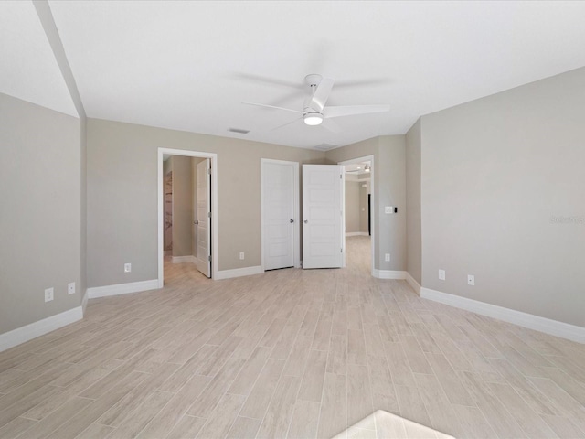 unfurnished bedroom featuring ceiling fan, a walk in closet, and light wood-type flooring