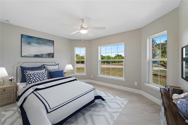 bedroom with ceiling fan, multiple windows, and light wood-type flooring