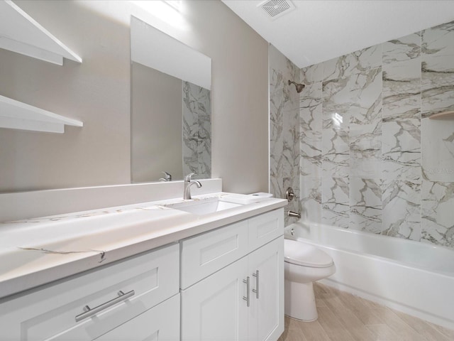 full bathroom with vanity, toilet, tiled shower / bath combo, and hardwood / wood-style floors