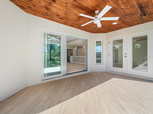 unfurnished sunroom with french doors, ceiling fan, a skylight, and wooden ceiling