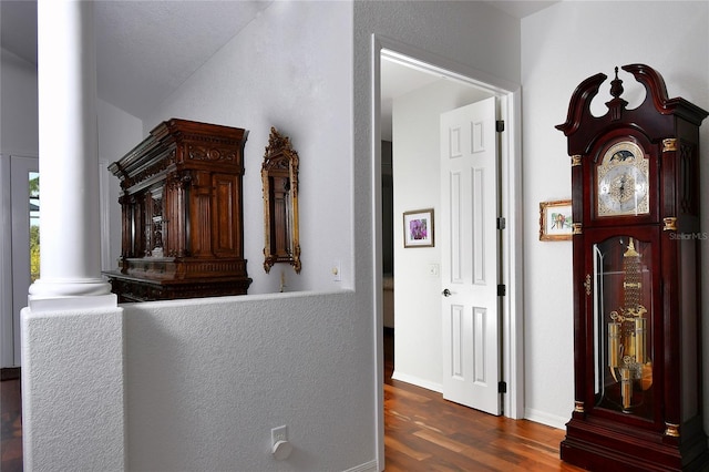 hallway featuring ornate columns and dark hardwood / wood-style floors