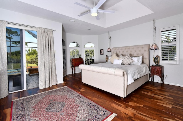 bedroom featuring dark wood-type flooring, access to outside, ceiling fan, and a tray ceiling