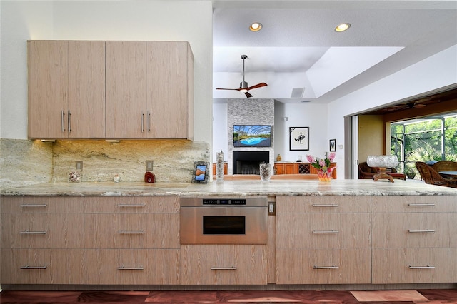 kitchen featuring light stone countertops, stainless steel oven, backsplash, and ceiling fan