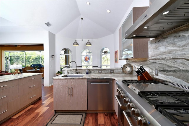 kitchen with appliances with stainless steel finishes, lofted ceiling, sink, a healthy amount of sunlight, and wall chimney range hood