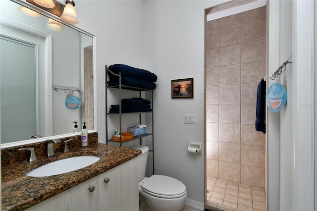 bathroom featuring vanity, tiled shower, and toilet