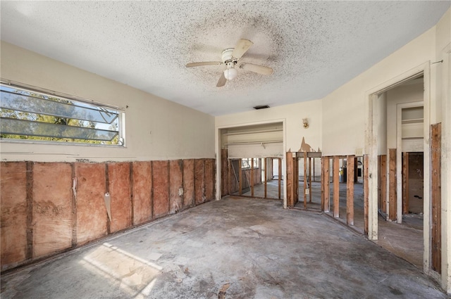 interior space featuring ceiling fan, concrete flooring, and a textured ceiling