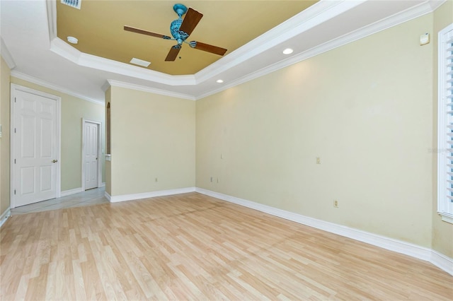 empty room with light wood-style flooring, baseboards, a raised ceiling, and a ceiling fan