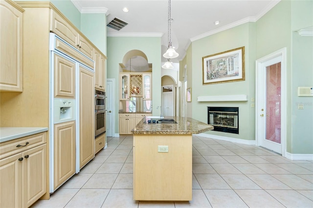 kitchen with visible vents, a kitchen island, ornamental molding, light tile patterned floors, and paneled refrigerator