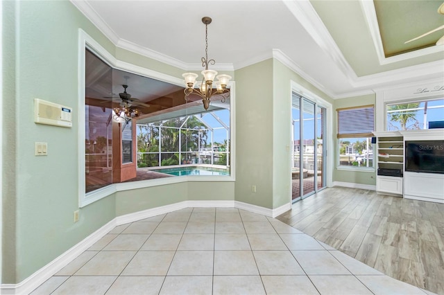 unfurnished dining area featuring a sunroom, a notable chandelier, a wealth of natural light, and ornamental molding