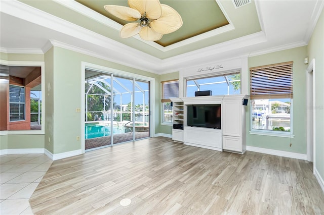 unfurnished living room featuring a wealth of natural light, a raised ceiling, ceiling fan, and a sunroom