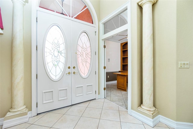 entryway with light tile patterned floors, baseboards, and ornate columns