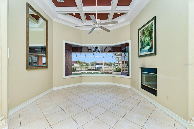 tiled empty room featuring a high ceiling, a ceiling fan, coffered ceiling, and ornamental molding