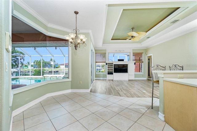 kitchen featuring visible vents, a tray ceiling, ornamental molding, ceiling fan with notable chandelier, and tile patterned floors