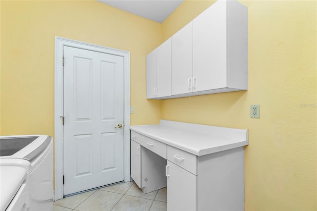 clothes washing area featuring light tile patterned floors, washing machine and dryer, and cabinet space