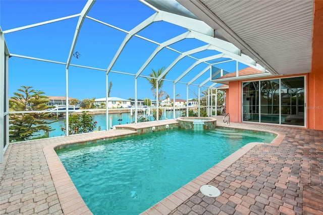 view of pool with a patio, a water view, a pool with connected hot tub, and a lanai