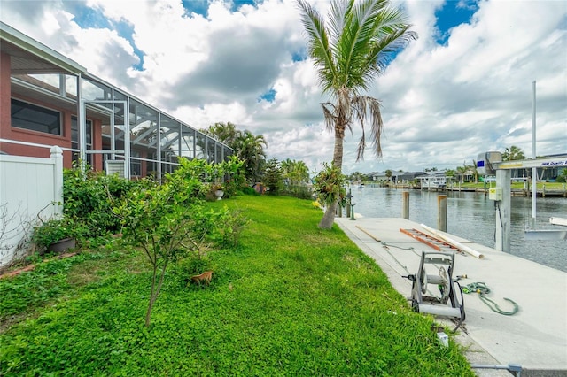 exterior space featuring a water view, a lawn, a lanai, and fence