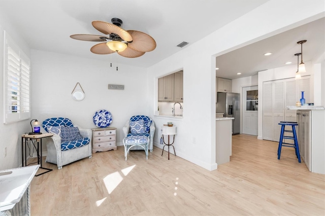 sitting room with ceiling fan, sink, and light hardwood / wood-style flooring