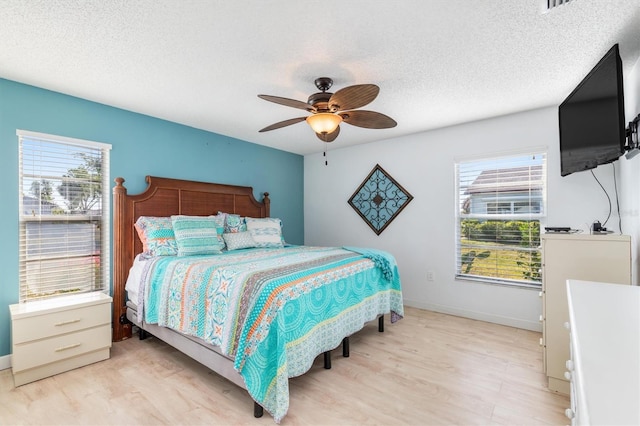 bedroom with multiple windows, ceiling fan, light hardwood / wood-style floors, and a textured ceiling