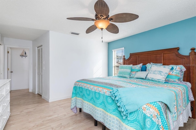 bedroom with ceiling fan, a closet, a textured ceiling, and light wood-type flooring