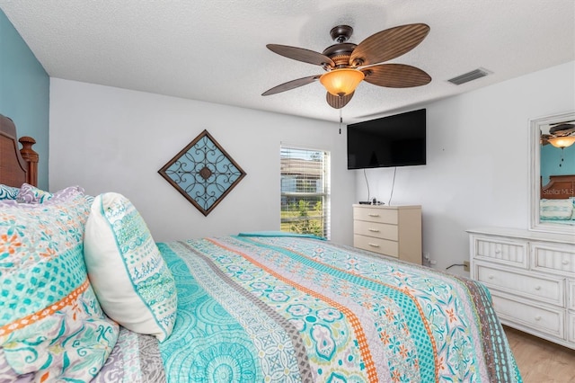 bedroom with ceiling fan, a textured ceiling, and light hardwood / wood-style floors